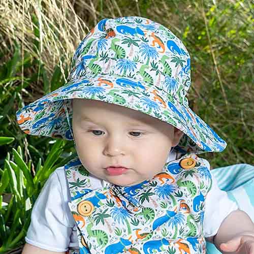 baby boy wearing Acorn Kids Prehistoric sun hat and matching romper