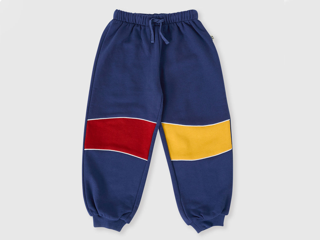 Color-blocked sweatpants with blue, red, and yellow sections on a light gray background