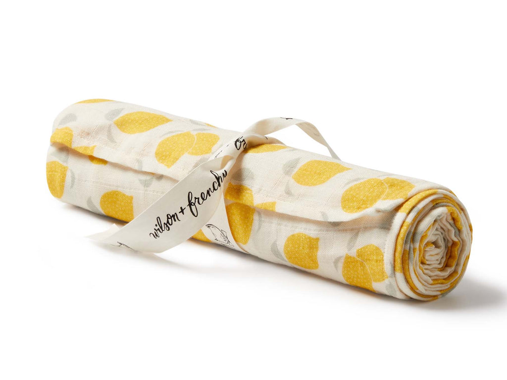 Rolled-up fabric with yellow lemons and a visible brand tag on a white background