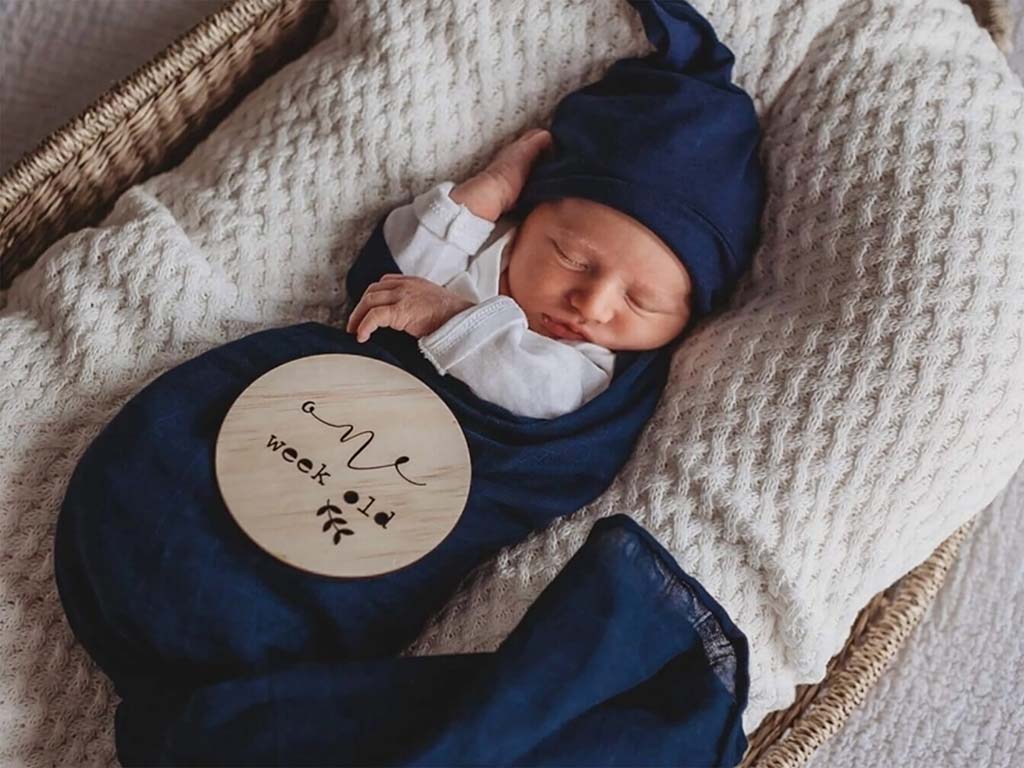 Baby boy swaddled in the Snuggle Hunny Kids Navy Swaddle and Beanie