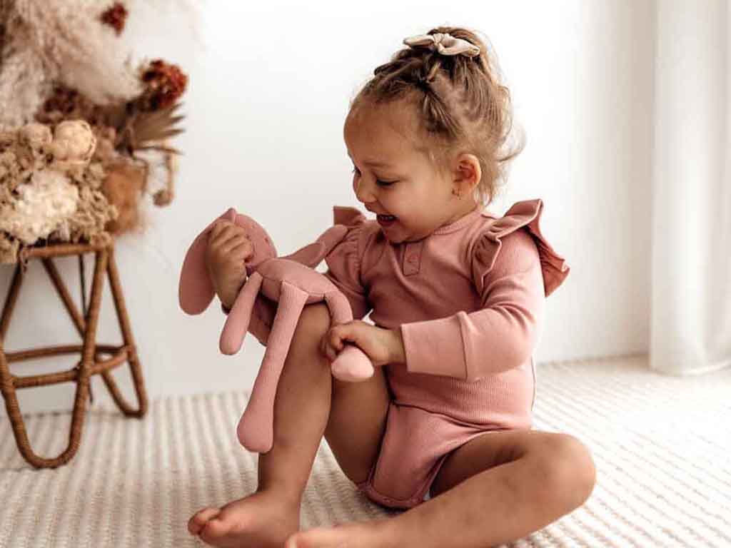 Child playing with Snuggle Hunny bunny in rose available at Young Willow