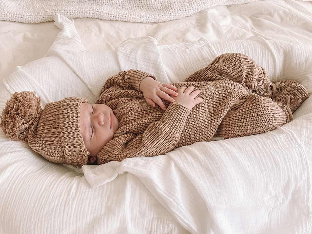 Baby sleeping in Ziggy Lou classic chunky knit romper in fawn